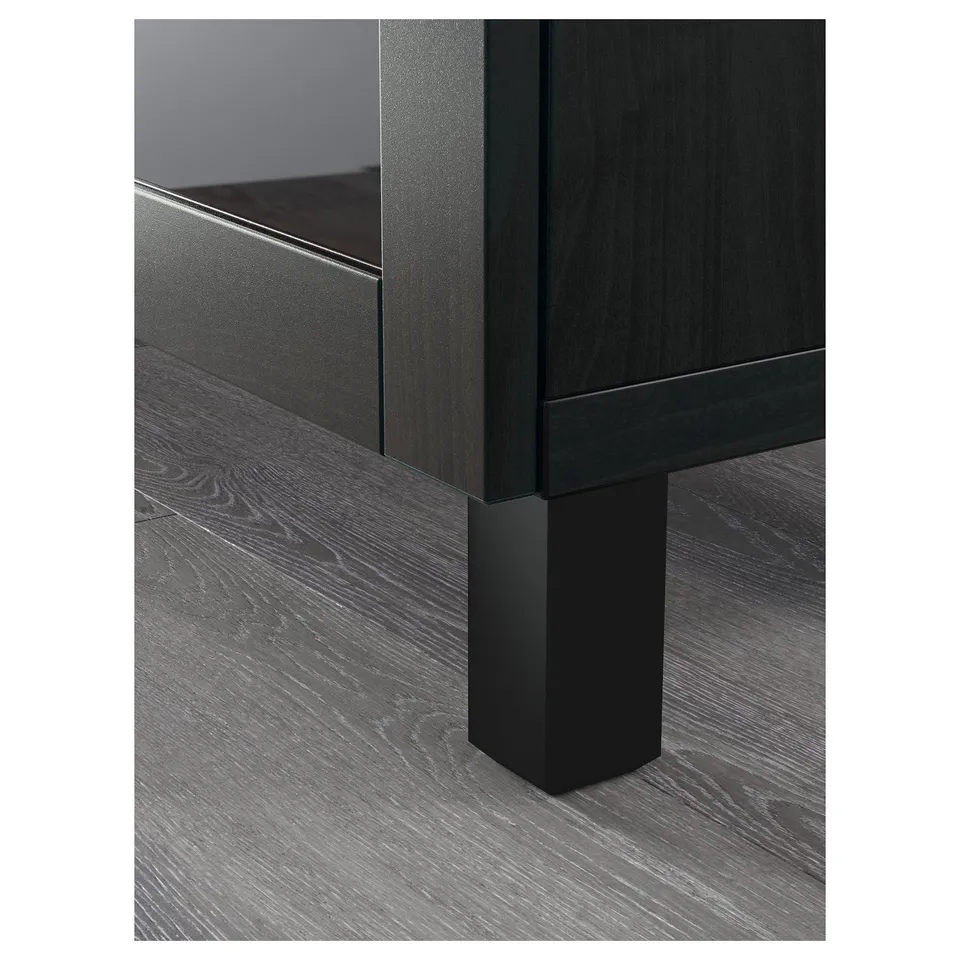 A sleek, modern sideboard with dark wood finish and angled legs, showing part of a black drawer and glass surface.