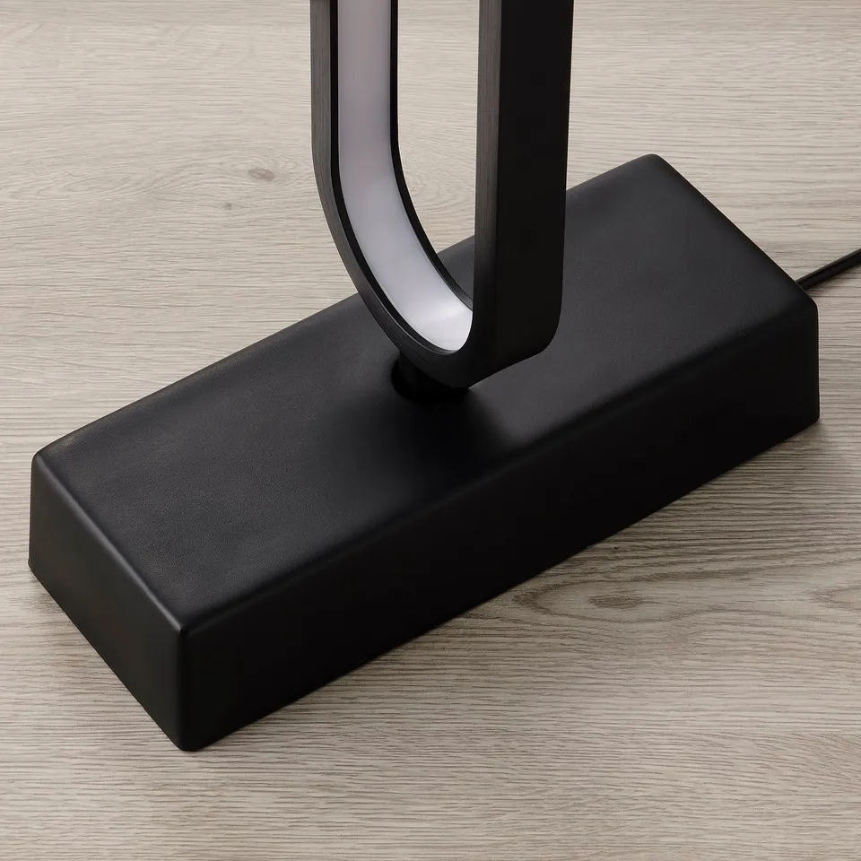 Modern black floor lamp with sleek design sits on wooden floor. Led light emits dynamic effects.