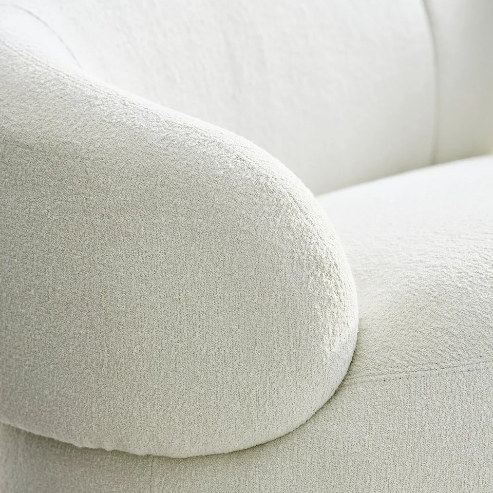Close-up of a plush, white sofa with rounded edges, showcasing high-quality fabric and stylish design.
