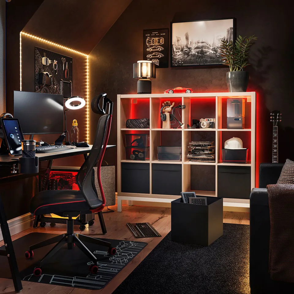 Modern home office with black KALLAX shelf unit, red led lights, black desk, black computer chair, monitor, keyboard, and guitar.