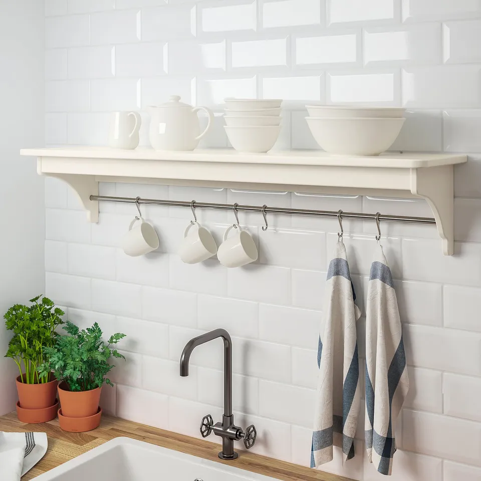 White kitchen shelf with hooks for mugs and towels, holding bowls, showcasing organisation and storage.