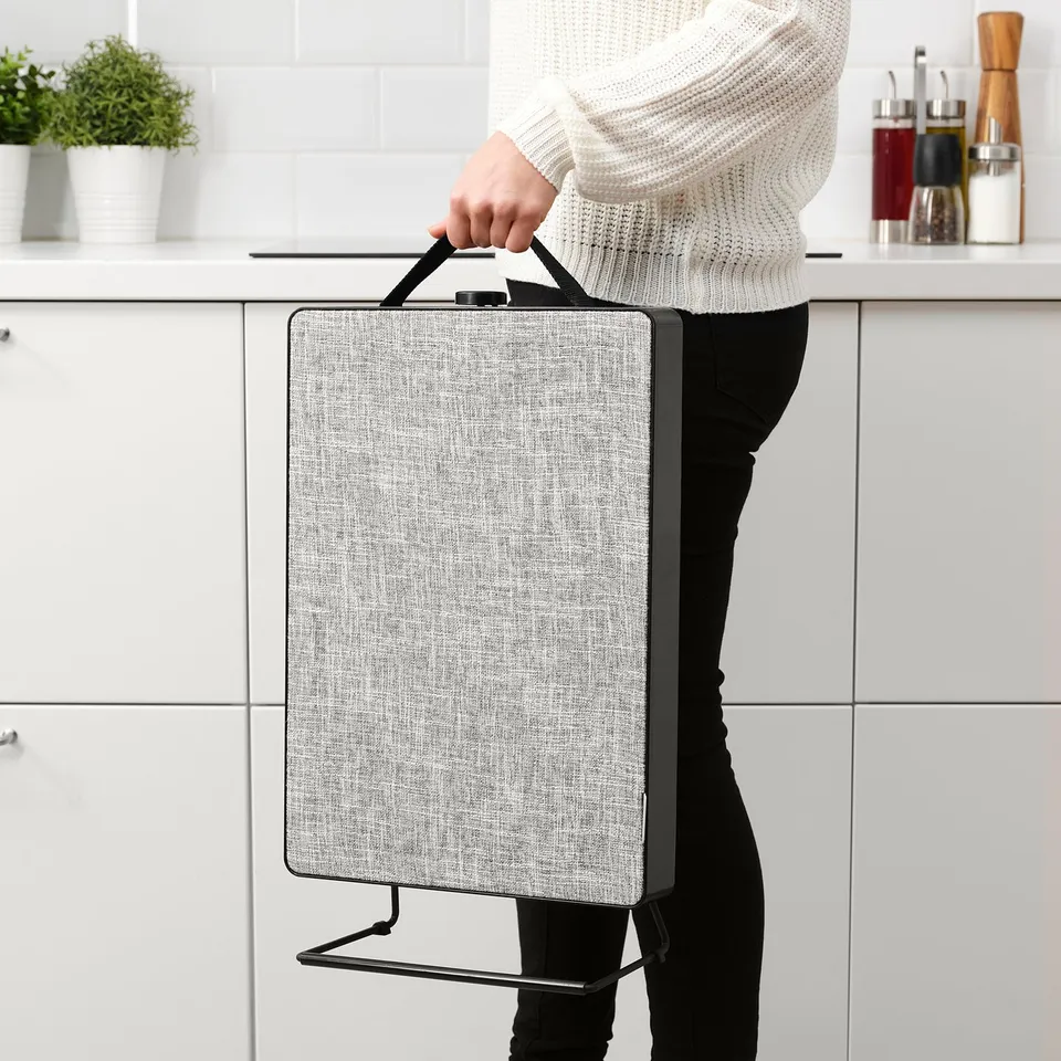 Person carrying portable air purifier by handle, suitable for various rooms, with adjustable fan speeds and easy wall mounting or floor placement.