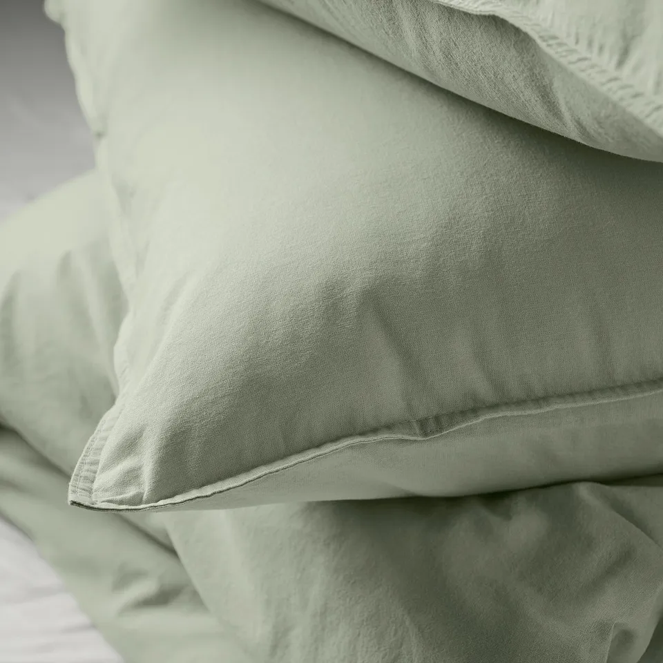Close-up of soft, light green pillowcases stacked neatly, showcasing smooth cotton texture.