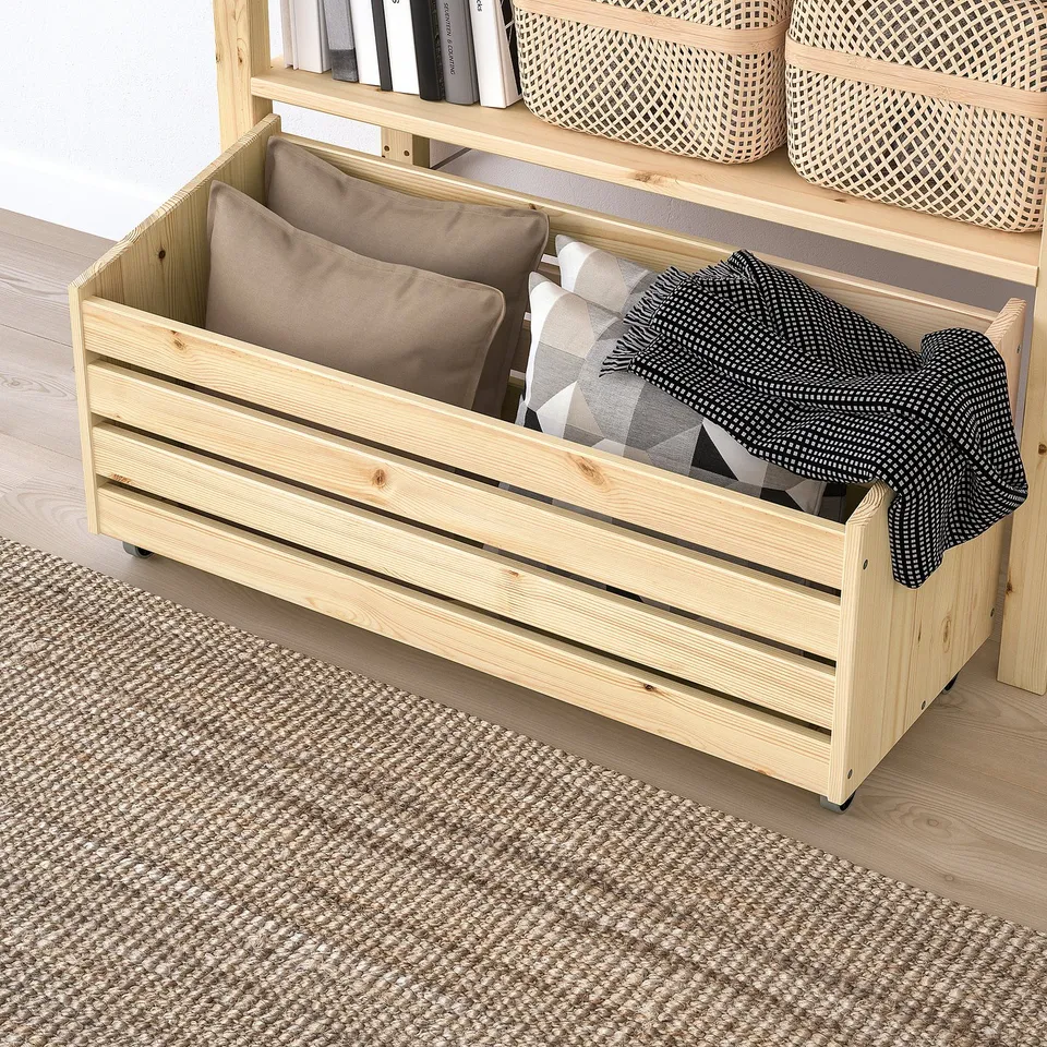 Wooden storage crate with wheels, filled with pillows and blankets, part of IVAR system.