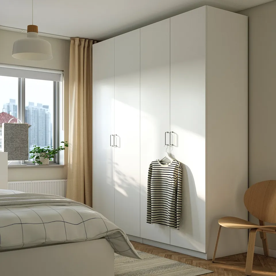 Modern bedroom with large white PAX wardrobe, striped shirt hanging, wooden chair, and bed with a window.