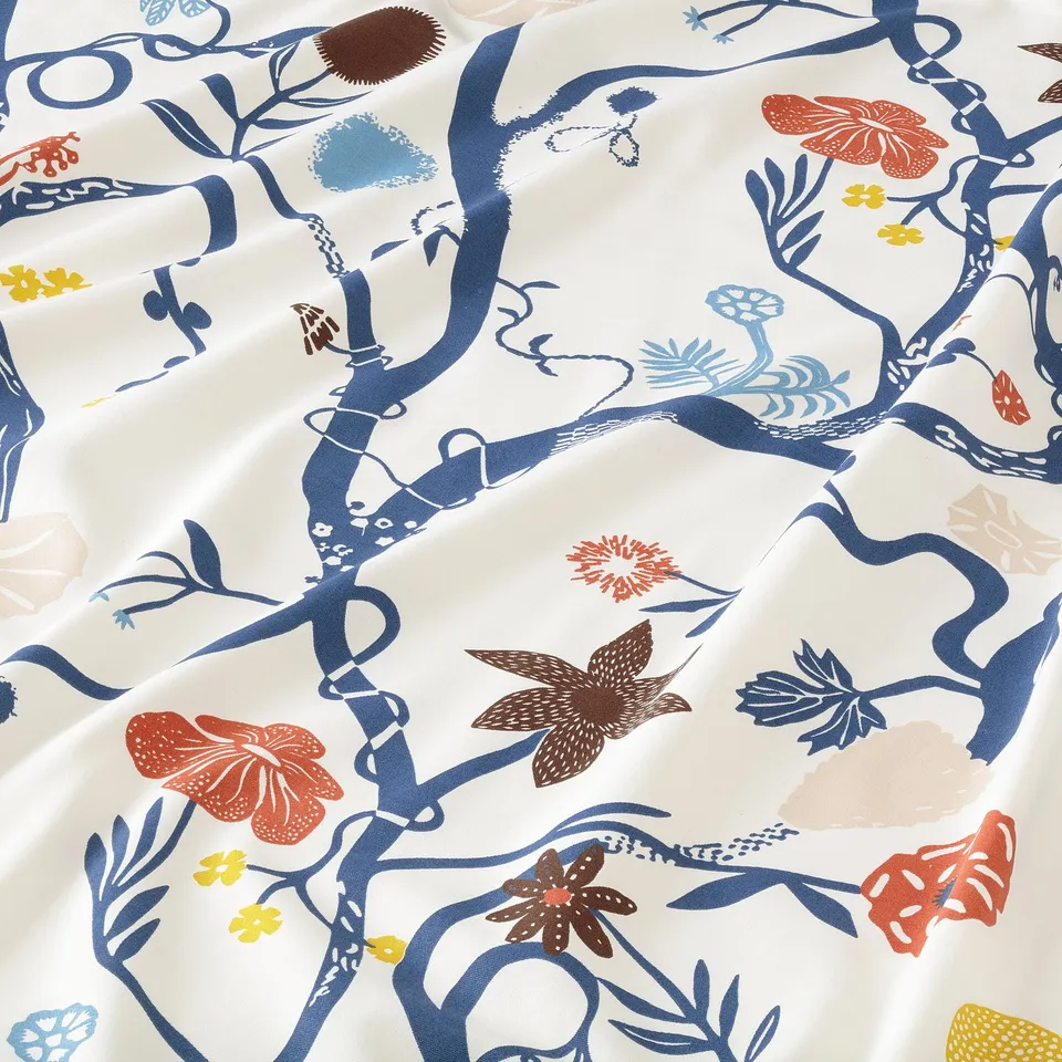 Bright floral fabric, intricate blue branches, orange, yellow flowers, detailed with butterflies. Soft, high-quality cotton texture.