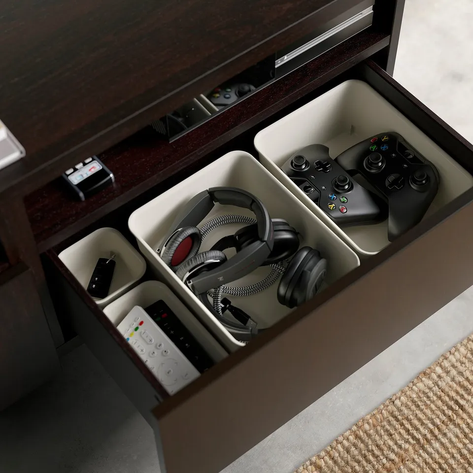 Open wooden drawer organiser for electronics: two game controllers, headphones, remote, and usb drive. Cable management and adjustable drawer runners.