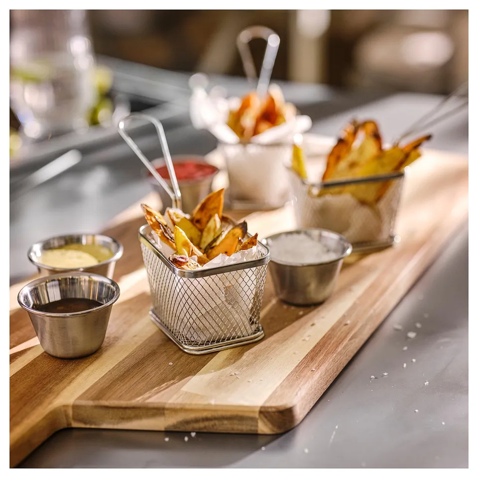 Small metal baskets filled with fried food on a wooden board, accompanied by sauce cups, perfect for serving grilled dishes at a bbq.