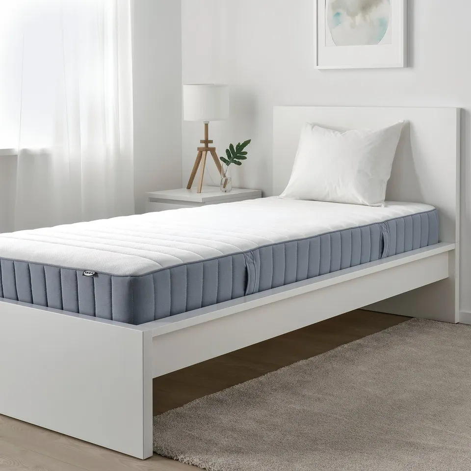 Minimalist bedroom with VALEVÅG mattress, bedside table, and wall art.