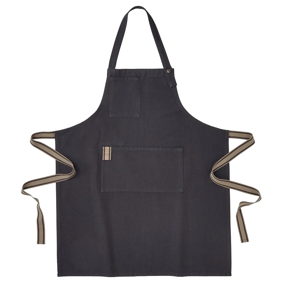 SANDVIVA black apron with brown ties, brass button, neck strap, loops, and pockets.