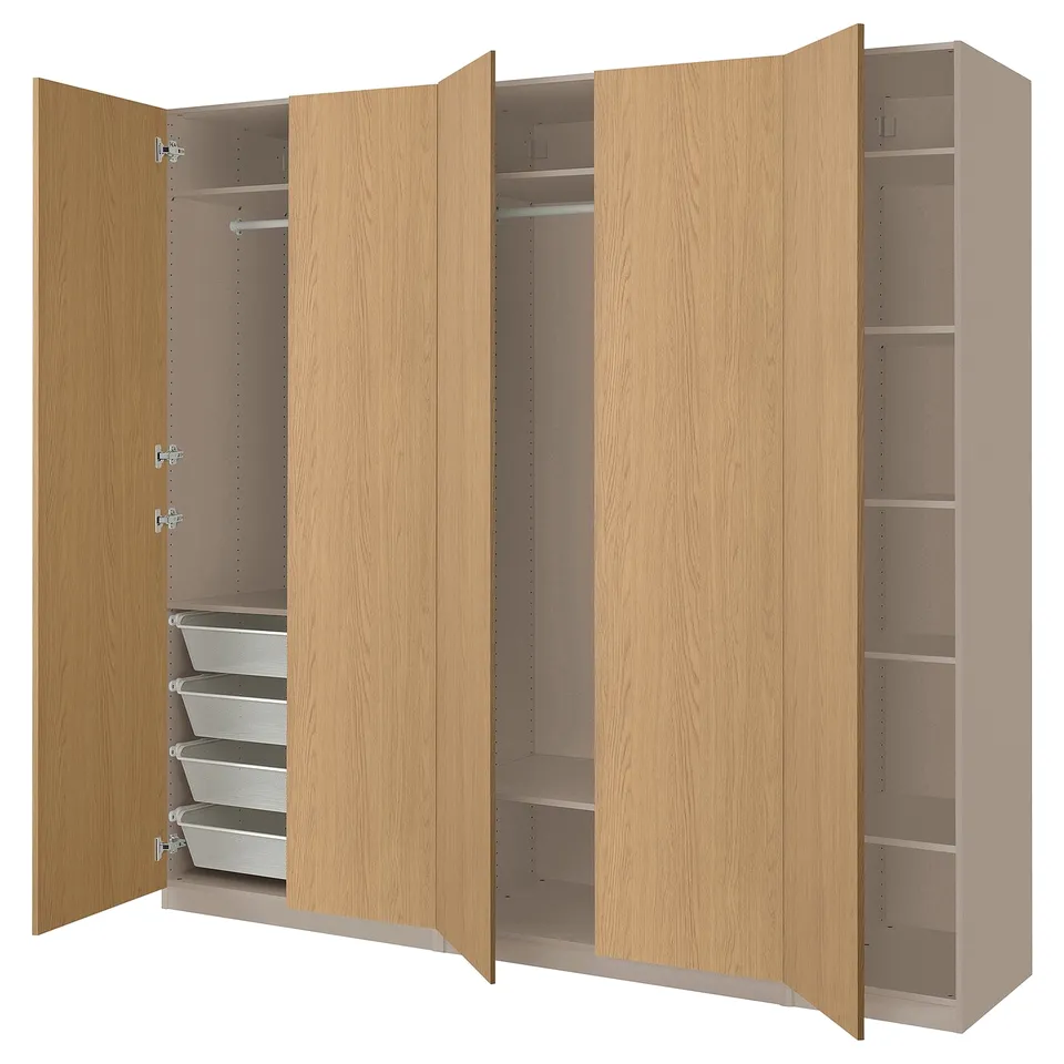 A light brown wooden wardrobe, PAX, with open doors revealing shelves and storage baskets.