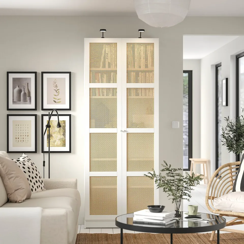 Modern living room with white BILLY bookcase featuring bamboo doors, a beige couch, circular coffee table, and wall art.