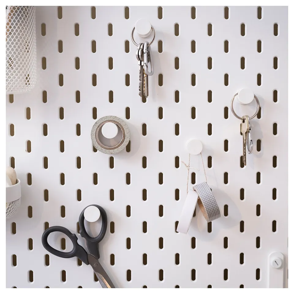 SKÅDIS pegboard with white hooks holds keys, scissors, and tape; perfect for home organisation.
