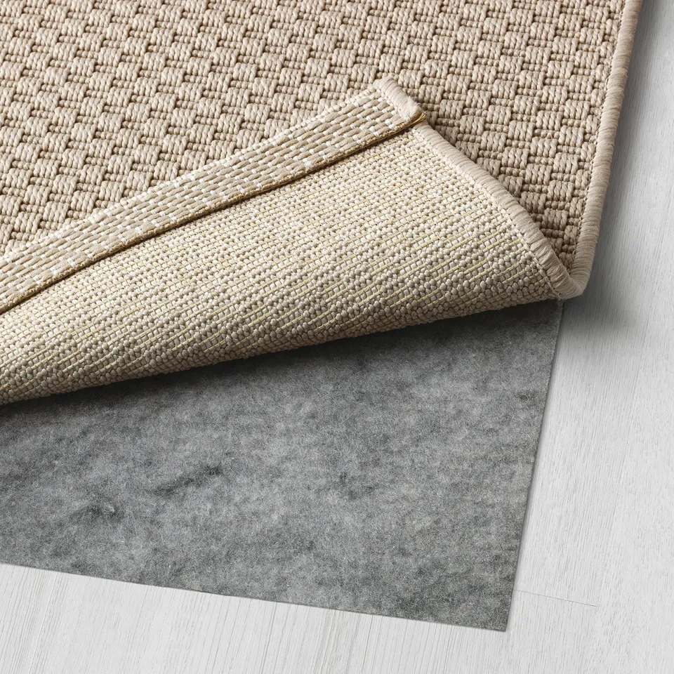 A beige woven rug placed on a grey underlay, designed for comfort and easy cleaning.
