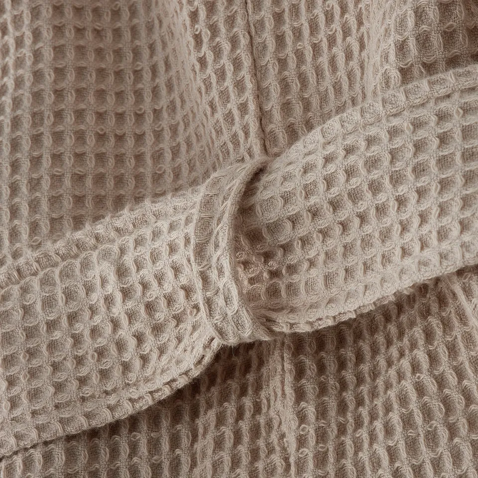 Close-up of plush, waffle-textured bathrobe, showing soft, absorbent fabric and stylish design.