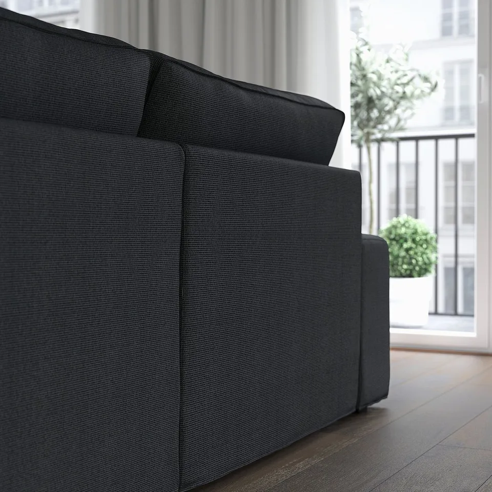Dark grey KIVIK sofa, deep cushions, pocket springs, low armrests, near large window.