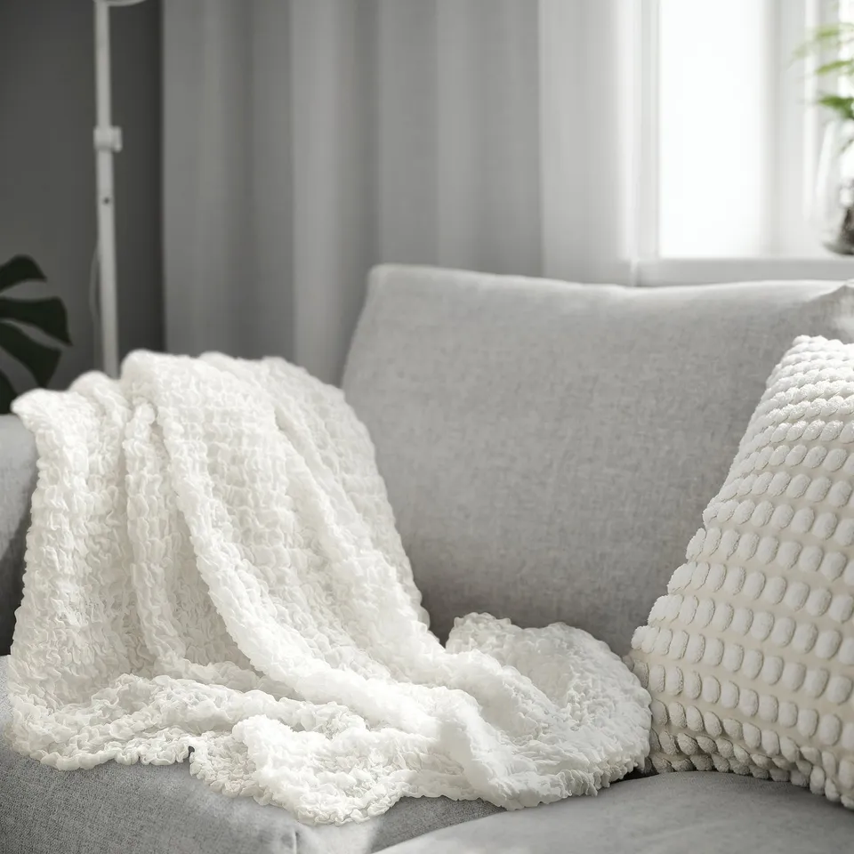 OFELIA throw blanket on grey sofa, 100% recycled polyester, soft & cosy.