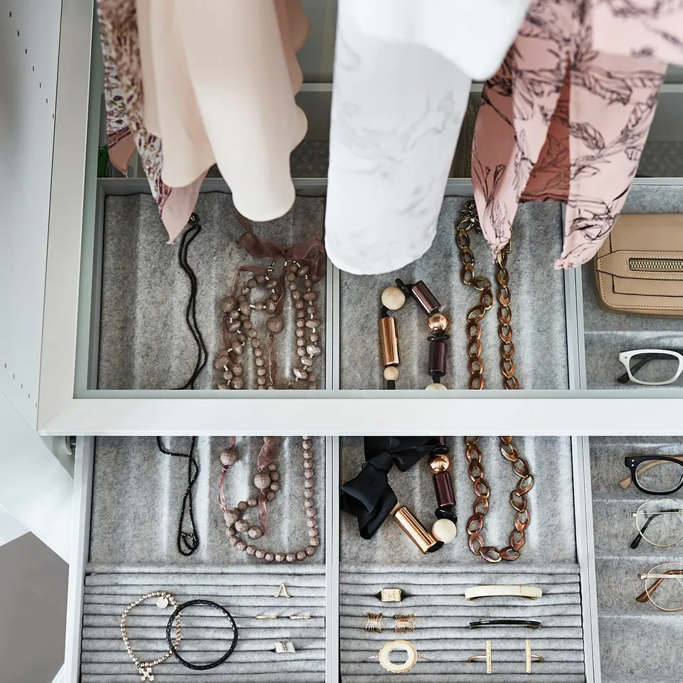 Jewellery and accessories in organised drawers. A person in pink floral attire accessing items.