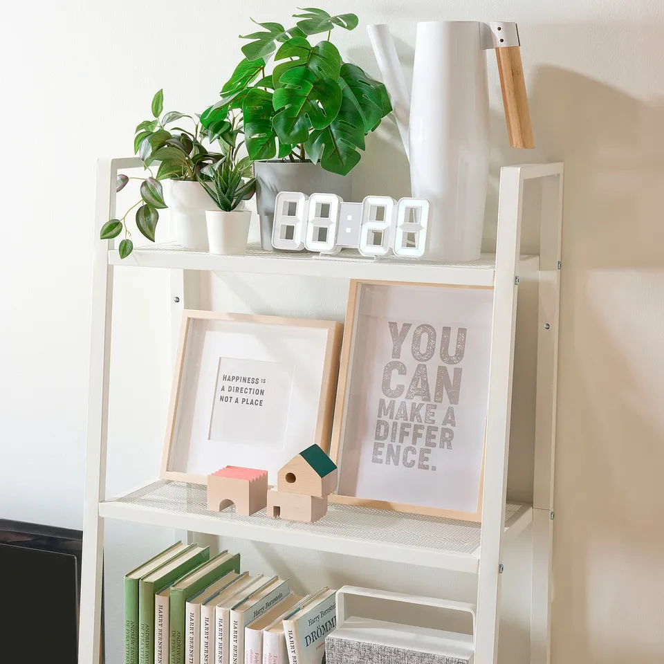 White shelf unit displaying books, plants, and decor; securely anchored to wall.