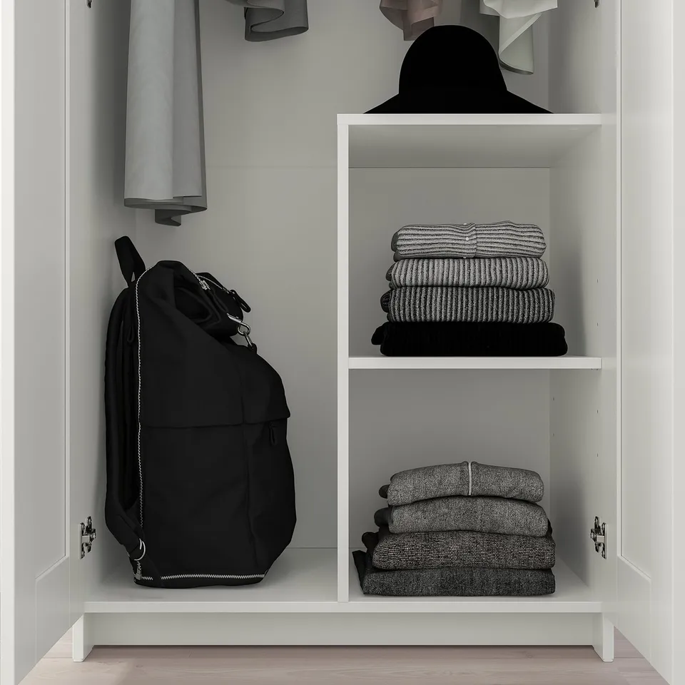 Closet with hanging bag, folded clothing, and shelf.