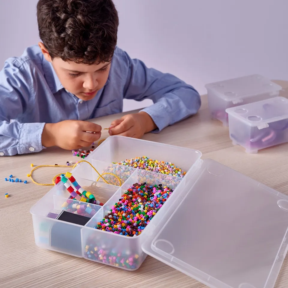 Boy crafting with colourful beads using plastic storage boxes.