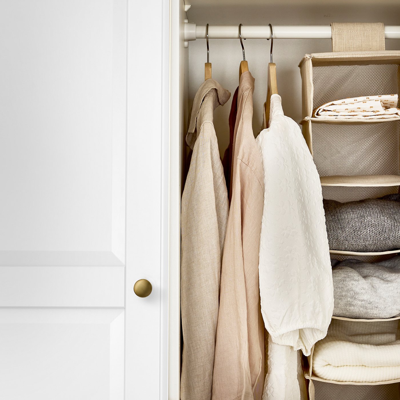 Closet with oregon beige jackets and folded linens.