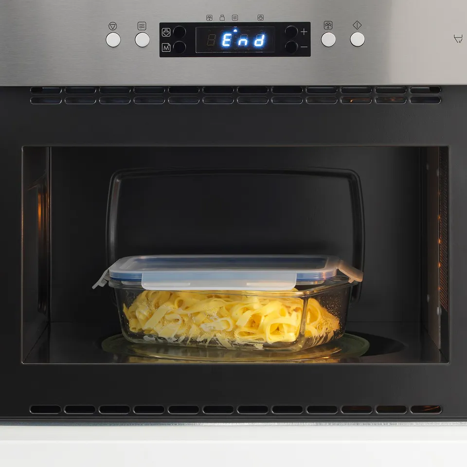 A microwave with a glass container inside, holding yellow food, covered with a lid. The display reads end.