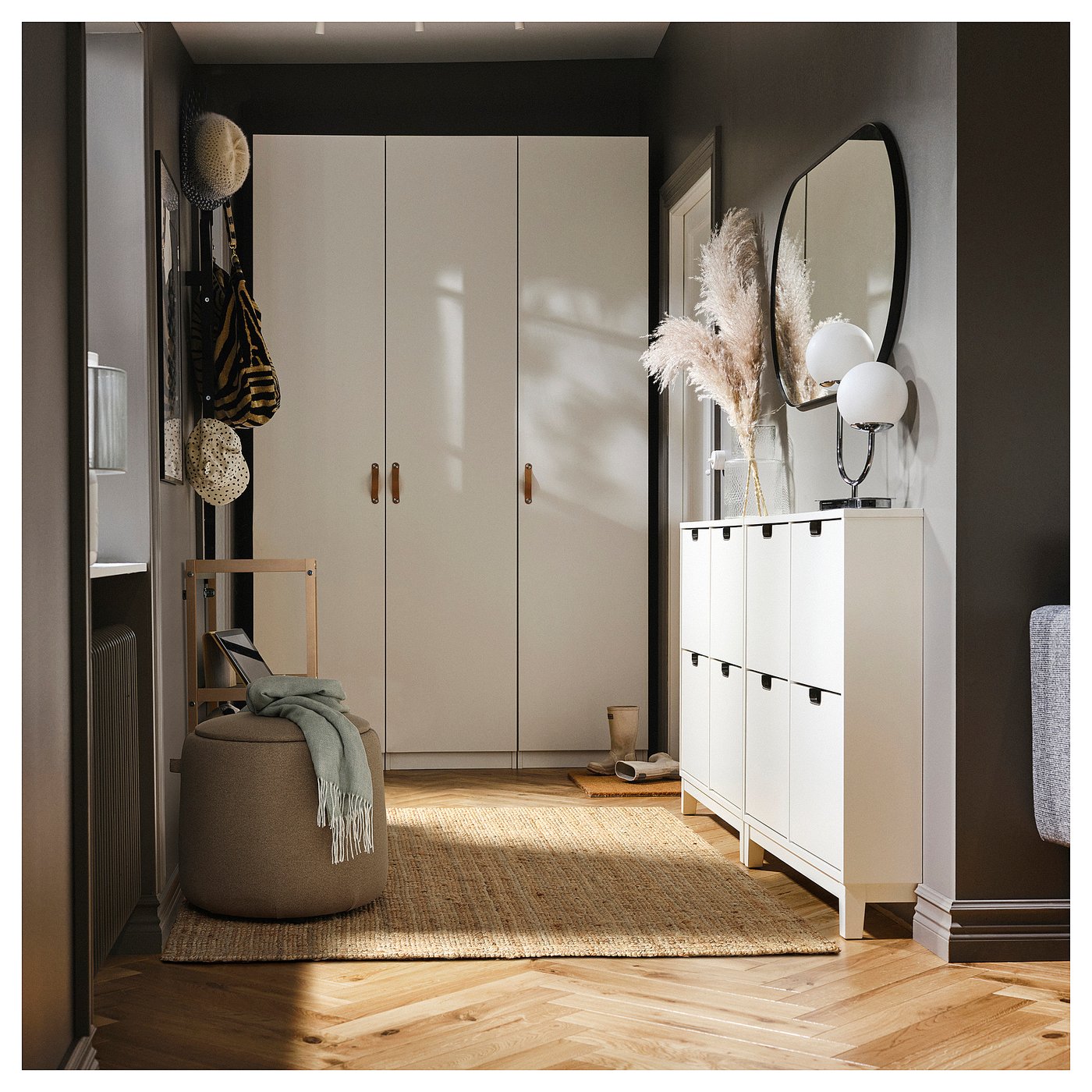 Modern entryway with white storage units, a round ottoman, mirror, and decorations.