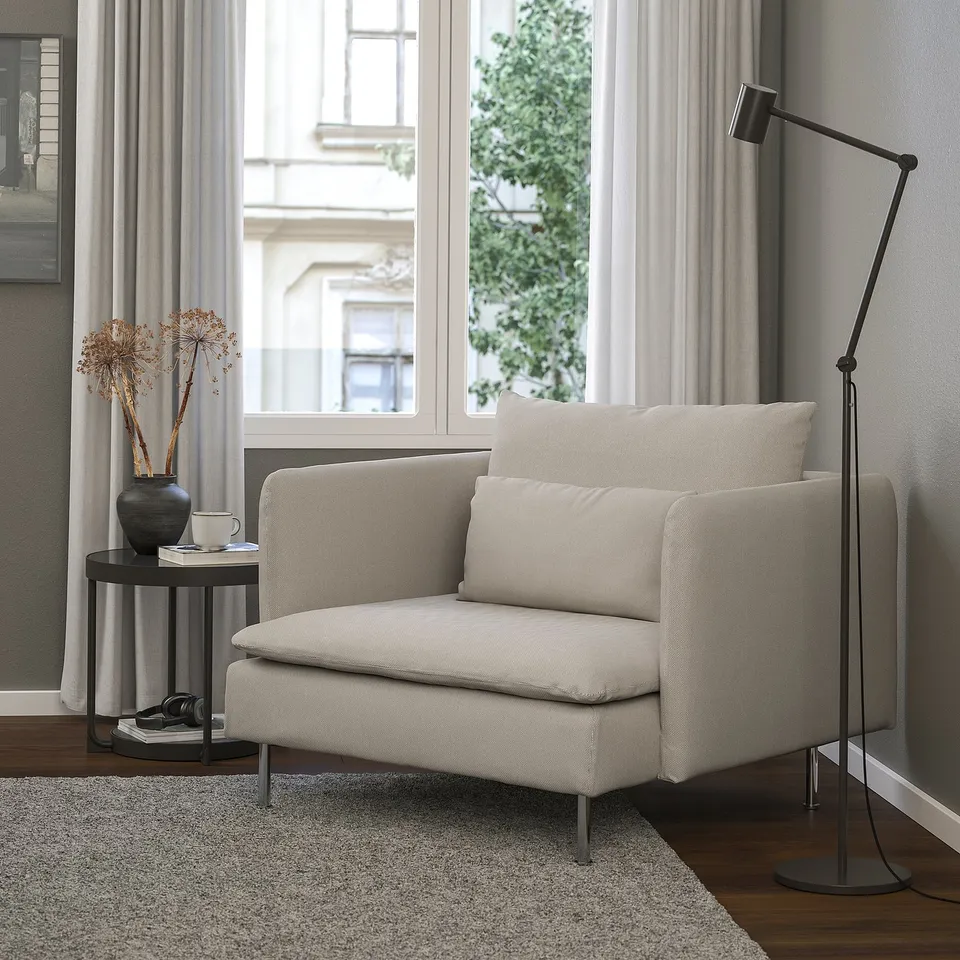 Modern living room: SÖDERHAMN armchair in beige, plush cushions, sleek design, beside small table with vase. Floor lamp stands tall nearby.