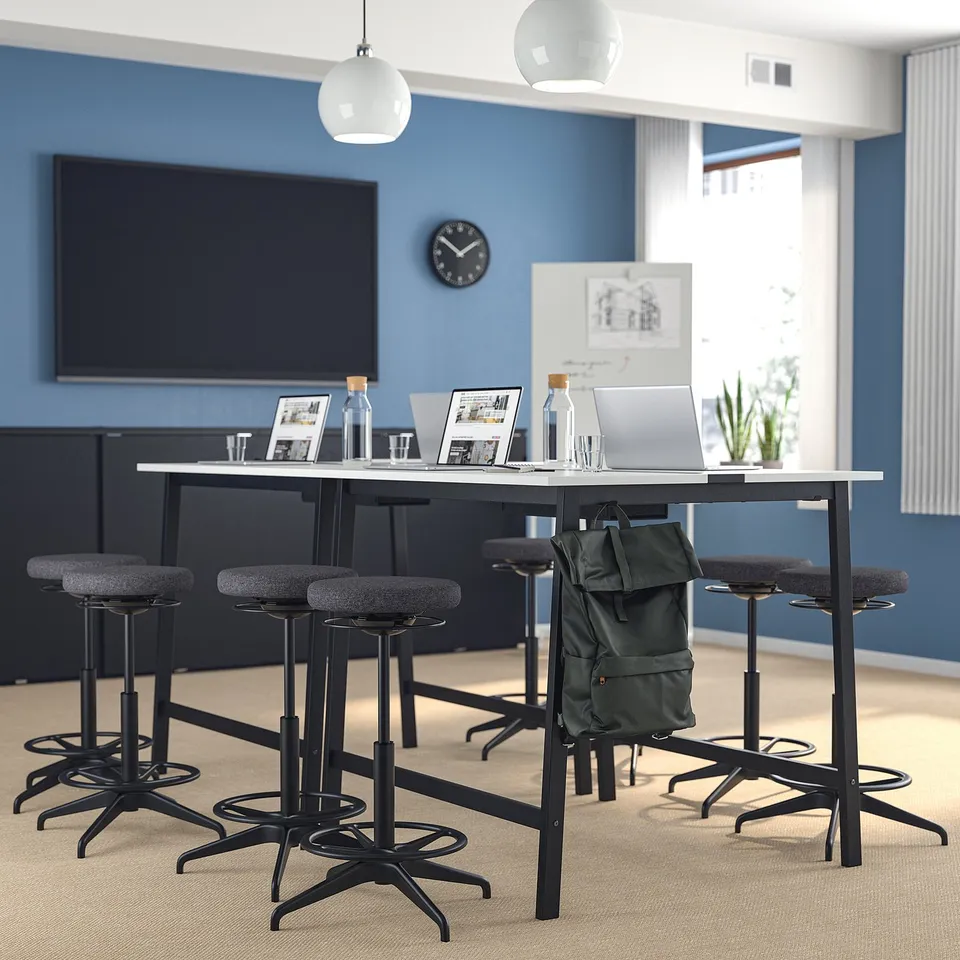 Modern blue office with MITTZON high conference table, grey barstools, laptop, and bags under table.