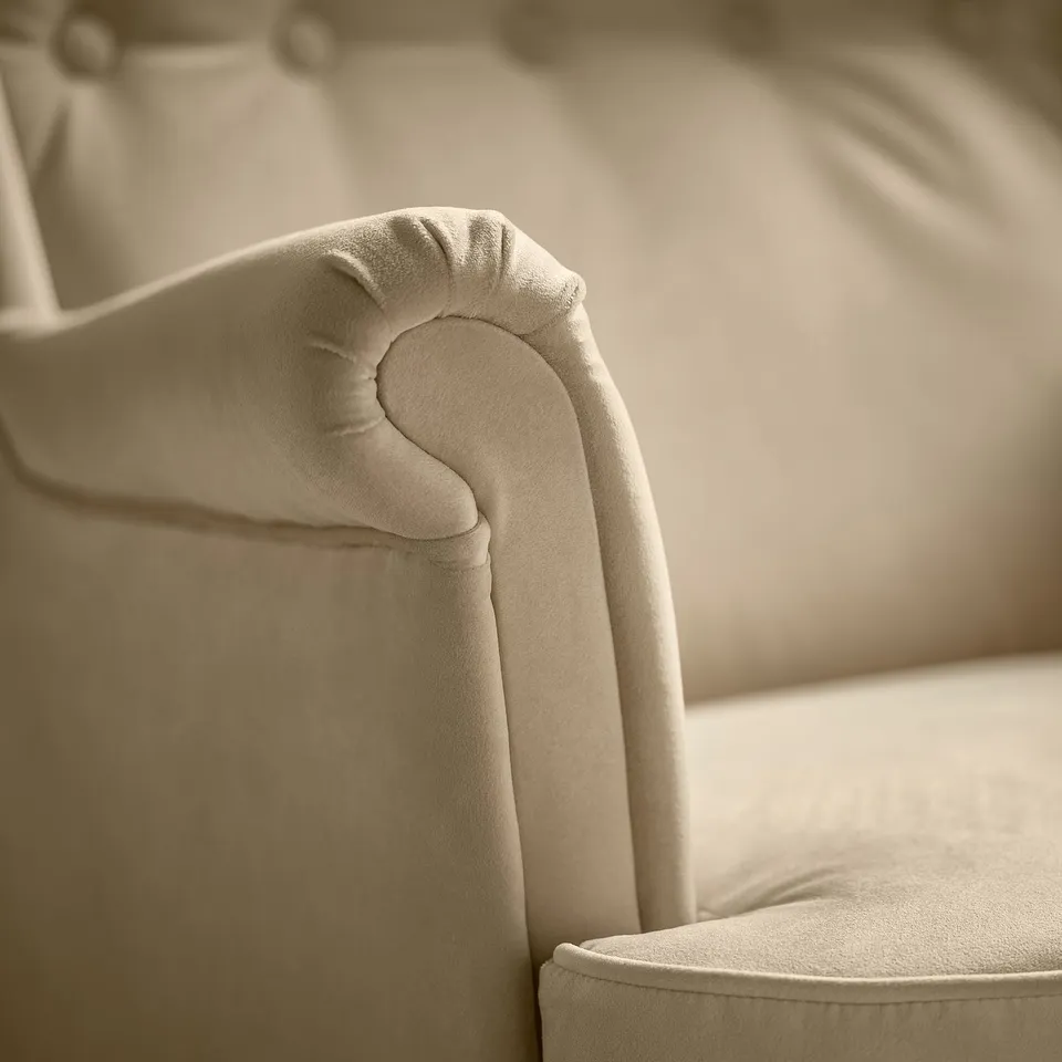 Close-up of a cushioned, high-back armchair corner, showcasing plush beige upholstery and sturdy, comfortable design.