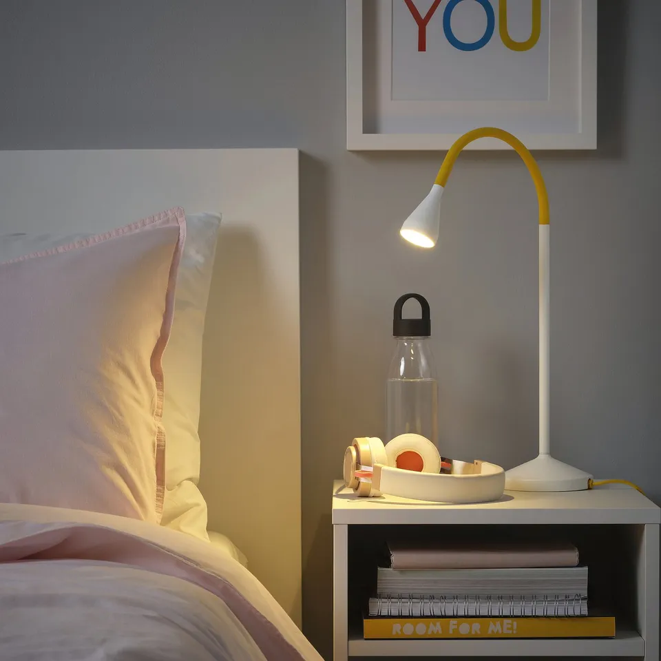 Bedside setup with NÄVLINGE lamp, water bottle, tape, and books. Lamp is bright, small, and flexible.