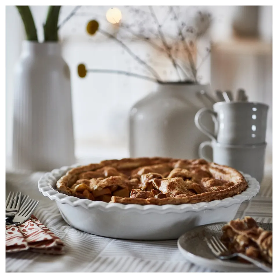 Golden baked apple pie in ceramic dish.