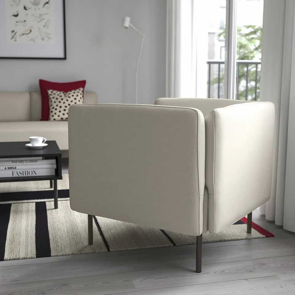 Modern living room with a beige lillehm sofa, featuring a red throw pillow and a black coffee table with books and a teacup.
