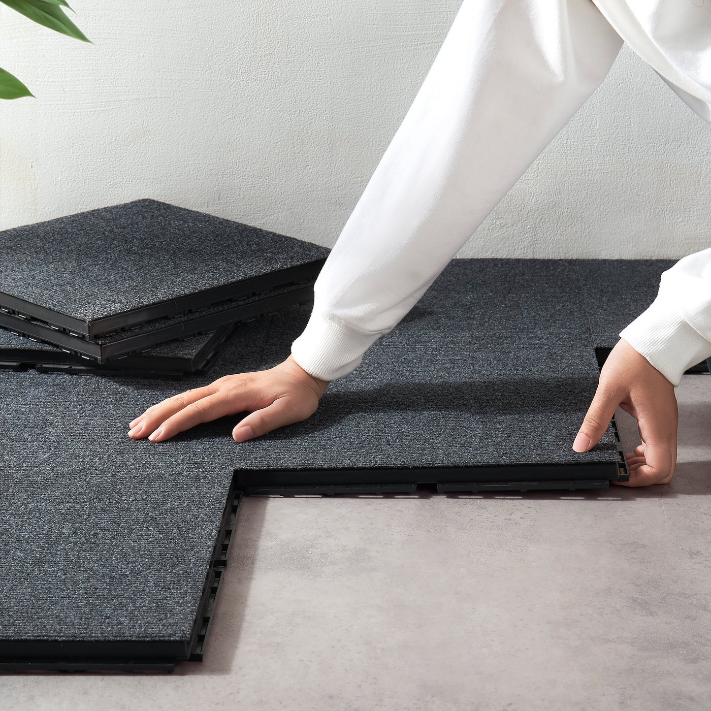 Person assembling grey RUNNEN outdoor floor tiles, easy to click together, suitable for balconies and terraces.