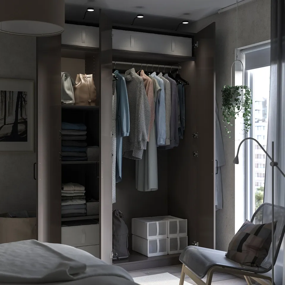 Bedroom with open wardrobe displaying clothes, folded clothes, and storage boxes. Wardrobe has dark wood finish and hanging garments.