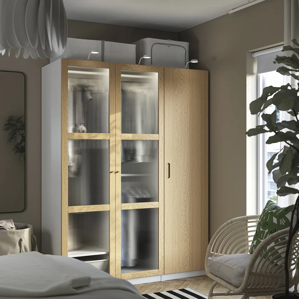 Modern bedroom with TONSTAD light wood wardrobe, chair, and plants.