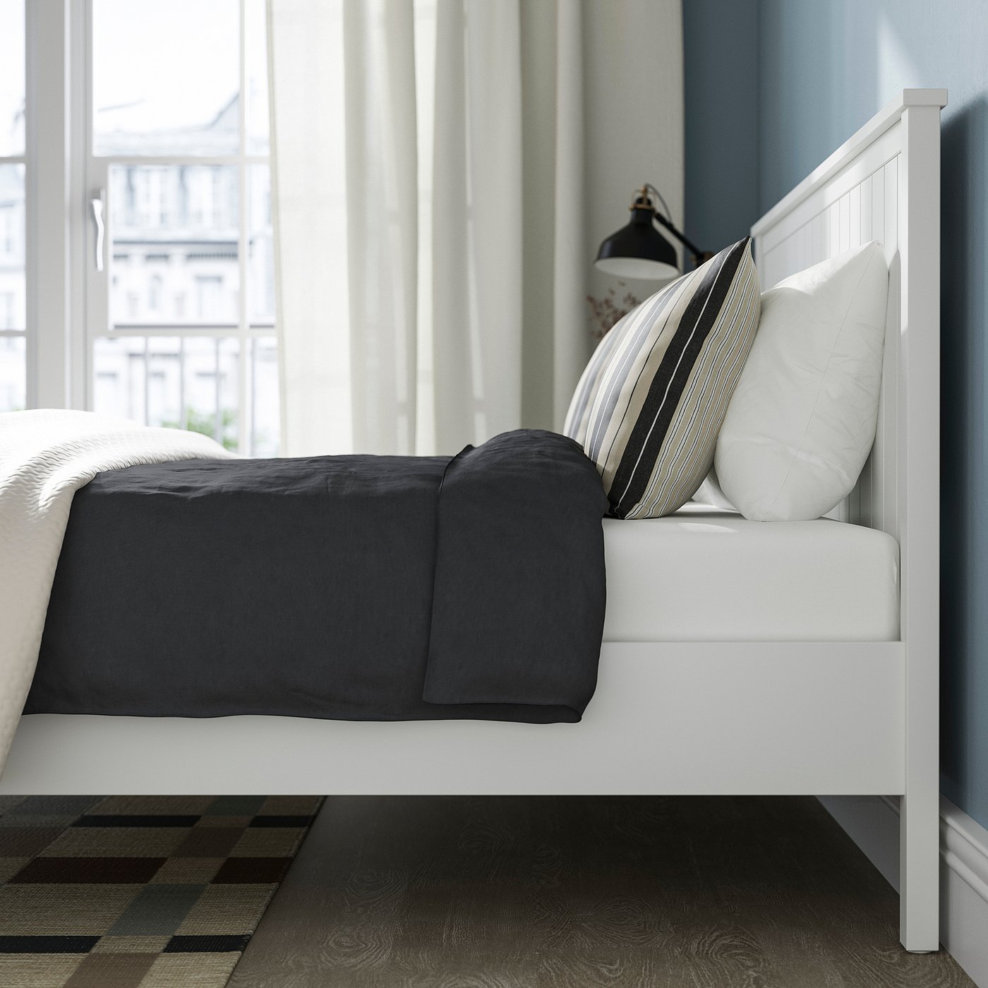 Traditional bed with dark bedding, slatted base, lamp