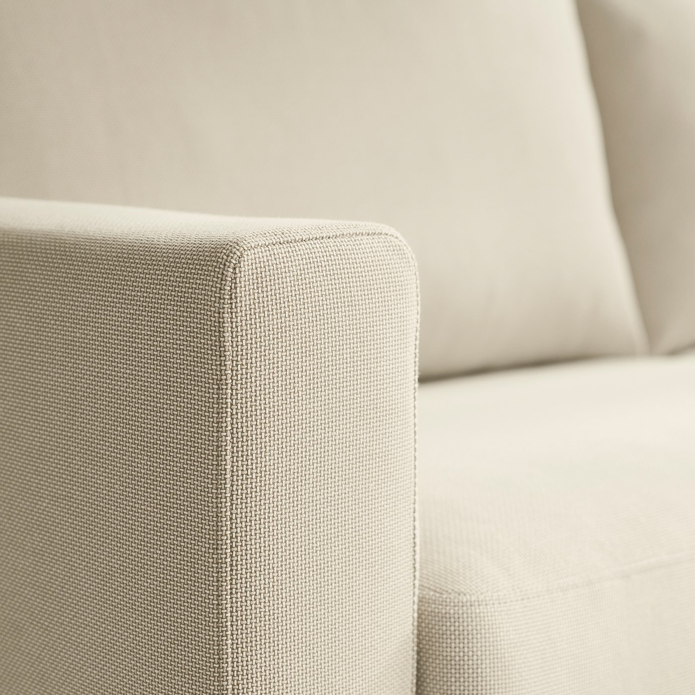 Beige sofa close-up, showing texture of woven fabric and sturdy cushions.