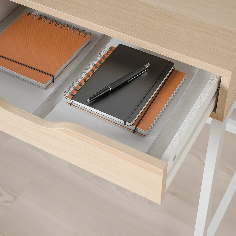 Open drawer of ALEX desk reveals organised notebooks and pen, showing built-in storage and cable management.