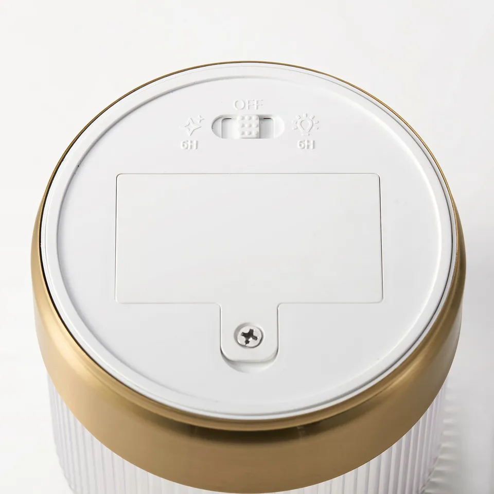 Circular led candle with gold trim, featuring timer and power controls, elegant design.