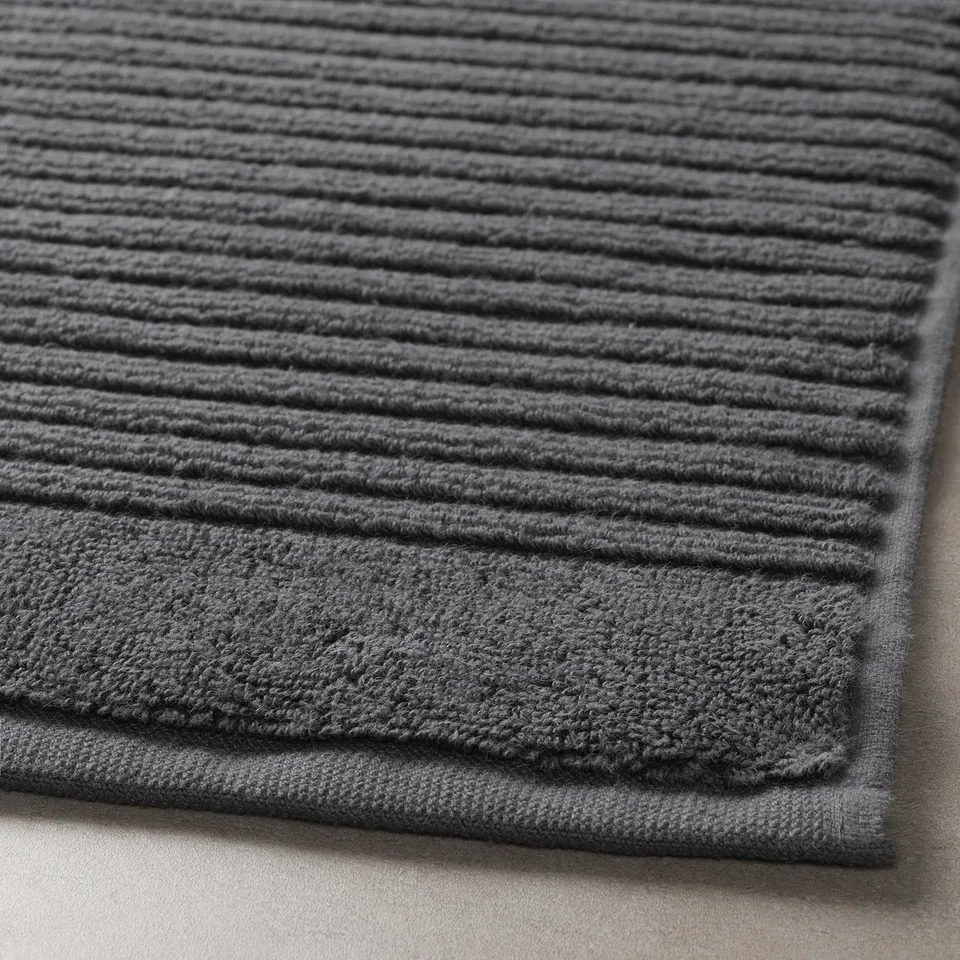 Close-up view of a plush, dark grey bath mat, showcasing its thick, textured cotton weave.