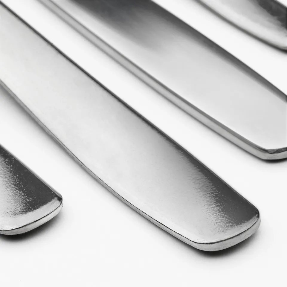 Pile of polished stainless steel cutlery - forks, spoons, knives. High quality, shiny finish, durable and clean.