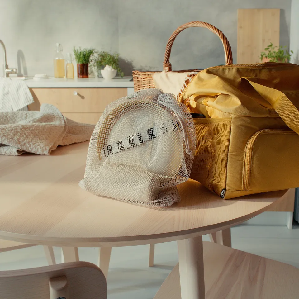 Yellow MARULK picnic set on table, includes mesh bag, tray, and mugs. Larger than wooden chair, smaller than wicker basket.