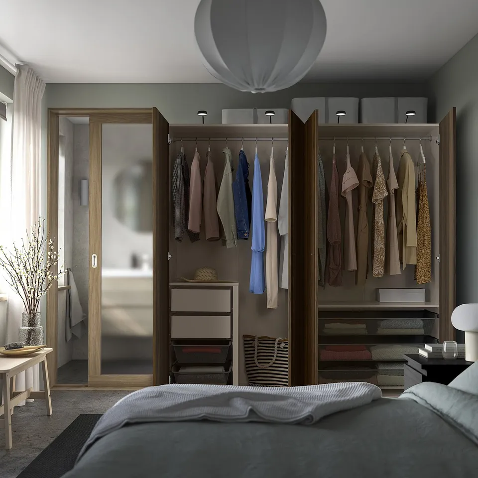 Bedroom with open wardrobe displaying clothes, shelves, and drawers; featuring adjustable feet and integrated lighting.