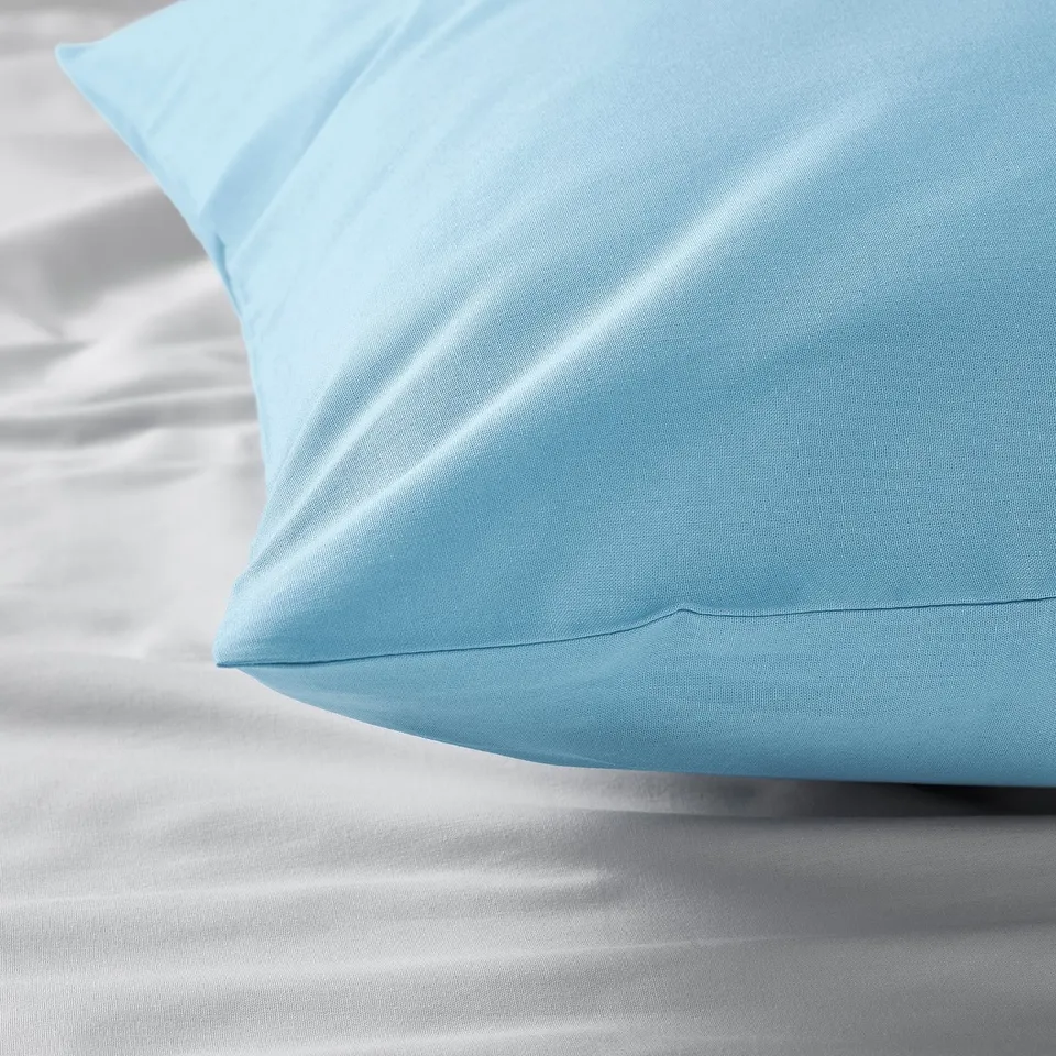 A close-up of a smooth, light blue pillowcase on a bed, highlighting its soft texture and quality.