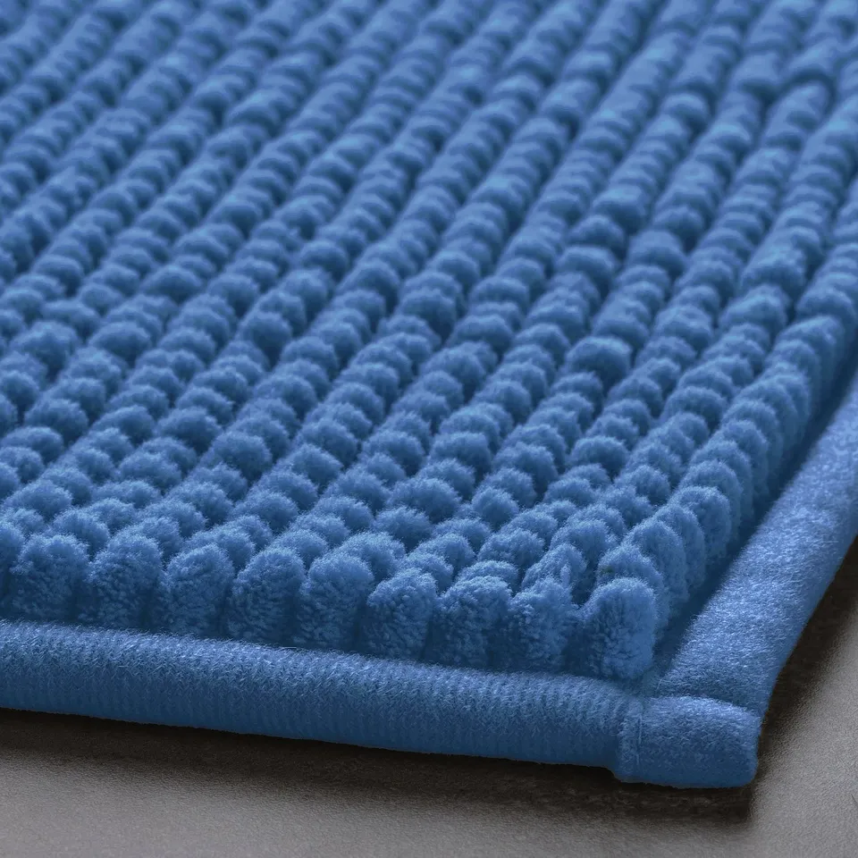 Soft blue bath mat with textured surface and plush edges.