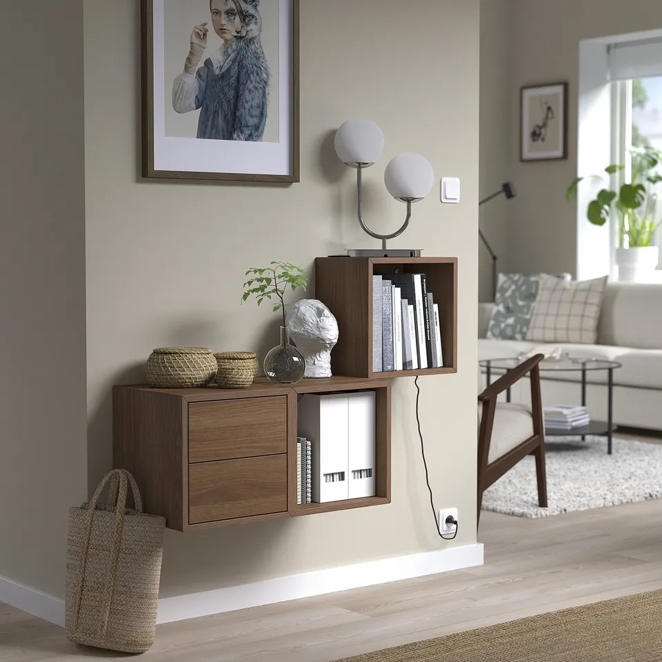 Living room with EKET storage, books, baskets, and decor. Warm, cosy ambiance.