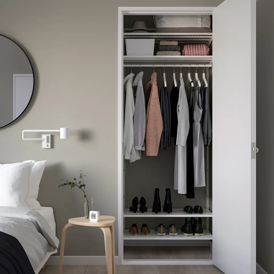 Modern bedroom with BOAXEL closet, bed, mirror, plant, clock.