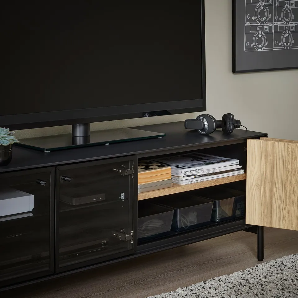Modern black tv stand with glass doors, remote-friendly panels, and cable management.